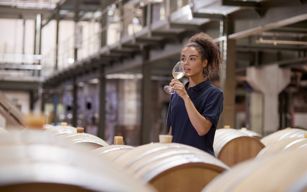 Young woman wine tasting in a wine factory warehouse